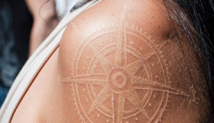 Tatuaggio bianco rosa dei venti sulla spalla